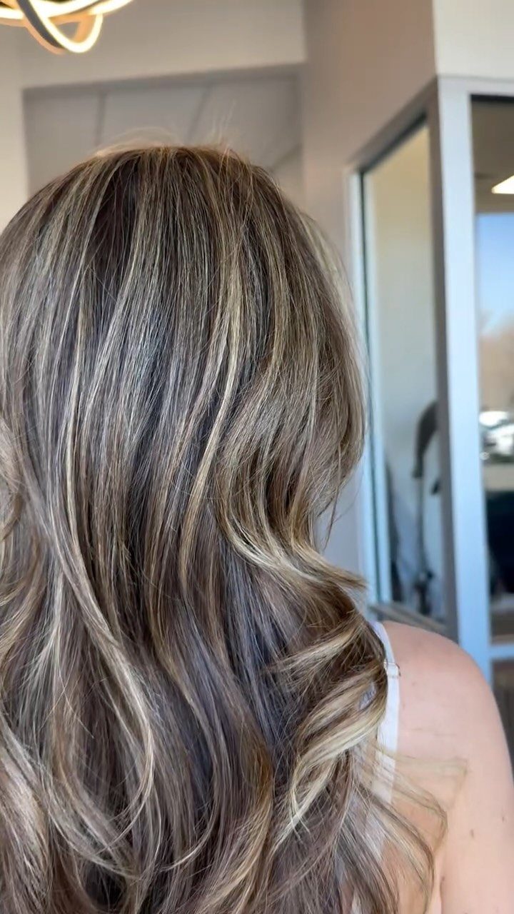 Long wavy dark brown hair featuring bright blonde ribbons in an indoor setting