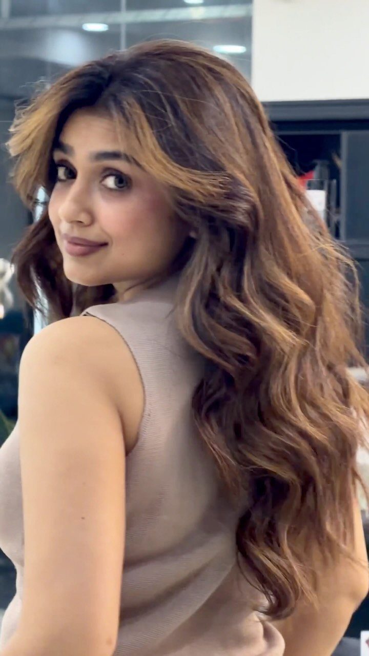 Woman with long cinnamon-brown hair and honey highlights framing her face