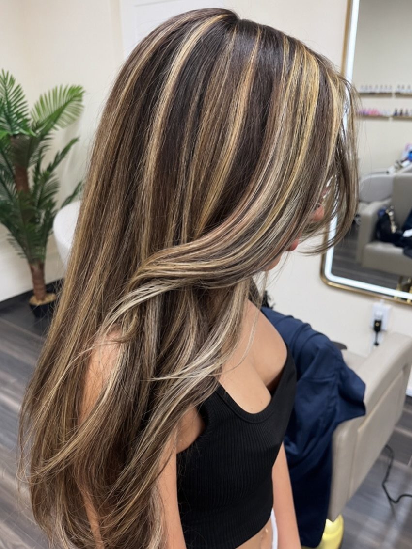 Long cool brunette hair with fine blonde ribbons shown in a salon