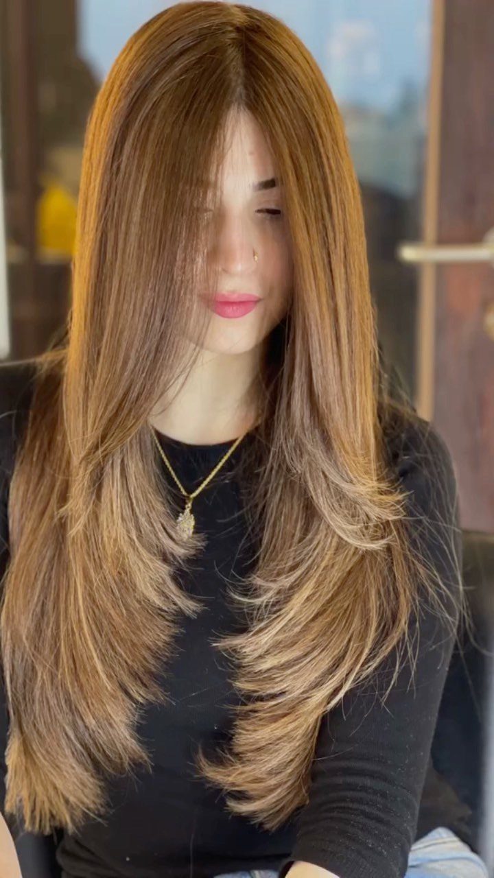 Woman with long layered brown hair and warm honey blonde highlights