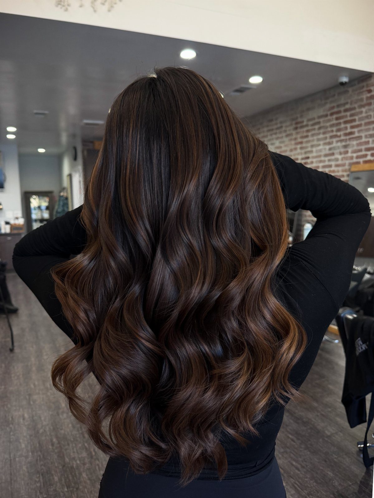 Long wavy dark brown hair with subtle multidimensional lighter brown highlights in a salon
