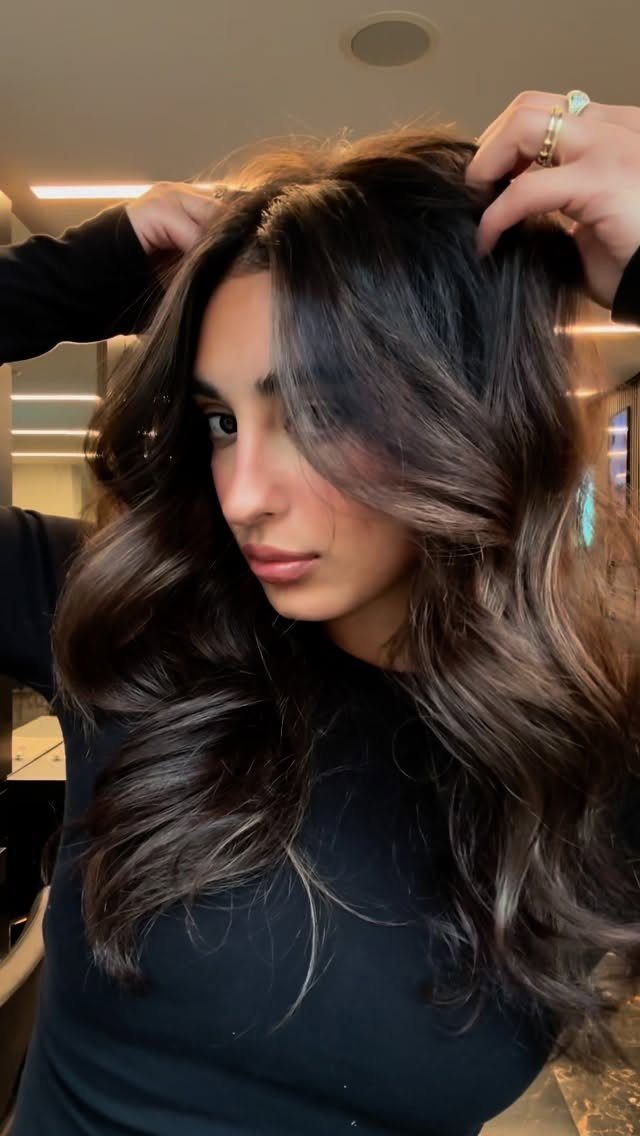 Woman displaying dark brown waves with softly blended dark blonde highlights