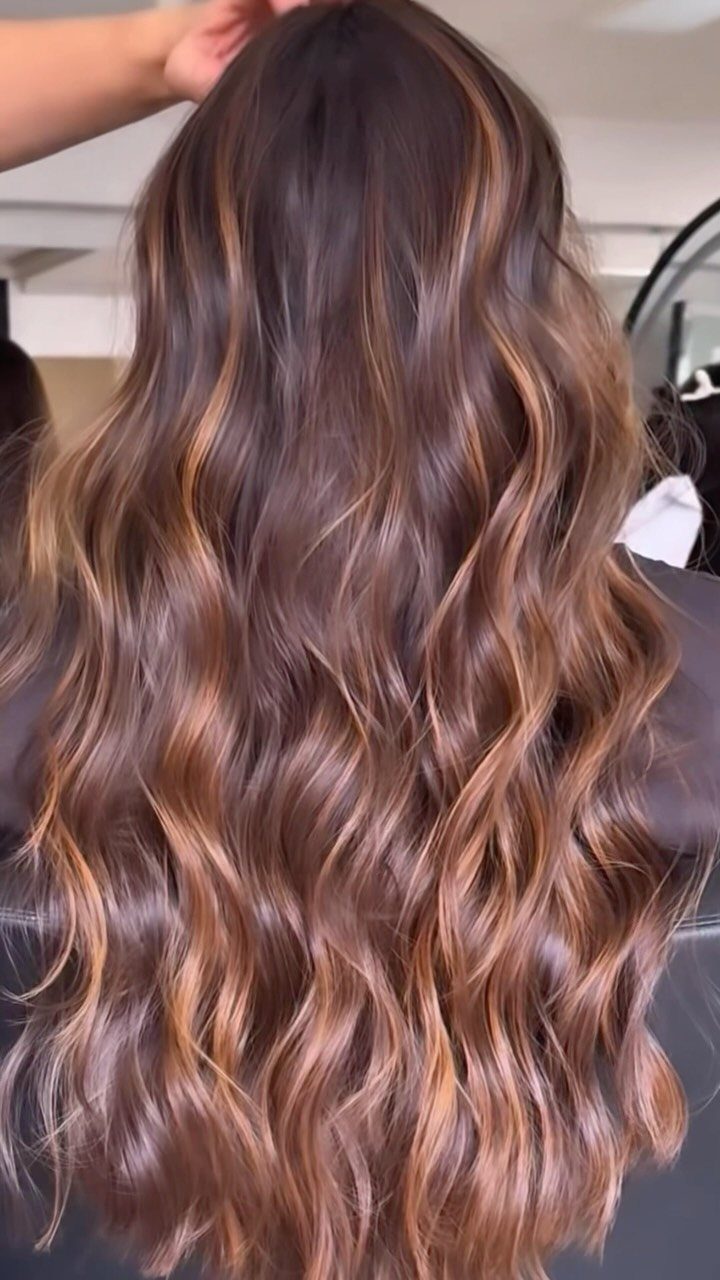 Long wavy brunette hair with dimensional auburn highlights viewed from behind