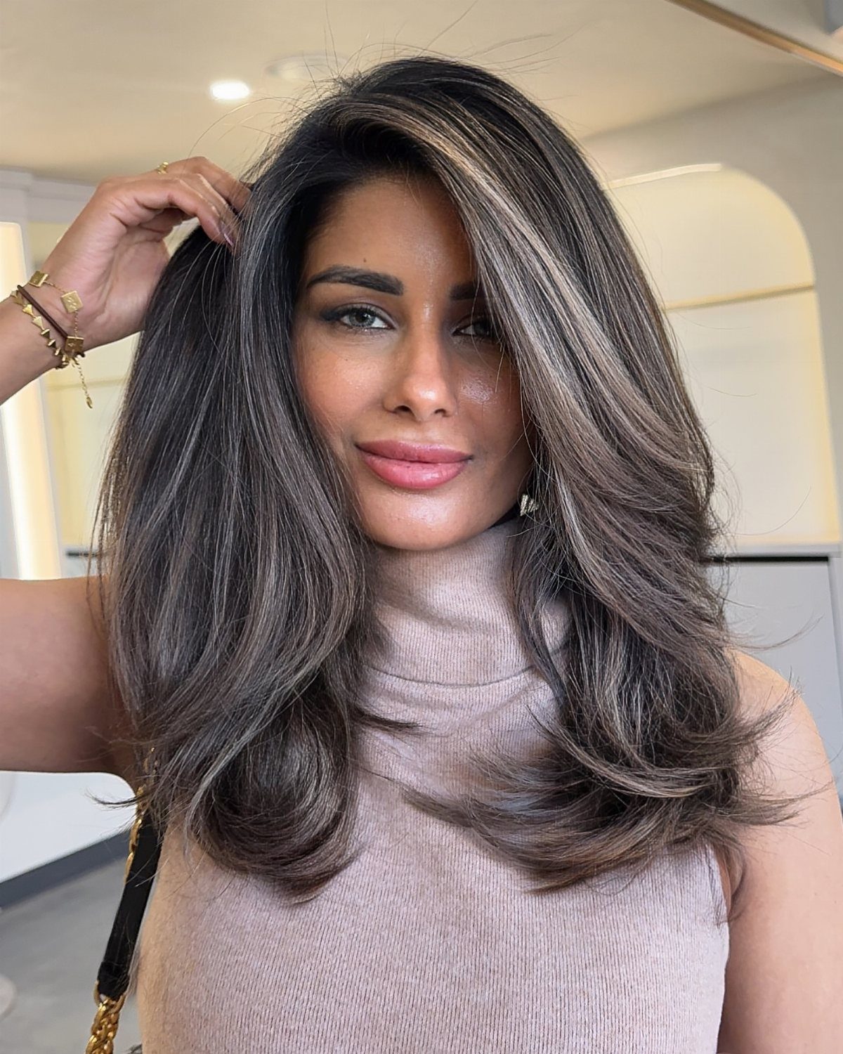 Woman showing long dark brunette hair with dimensional brown highlights and layered waves