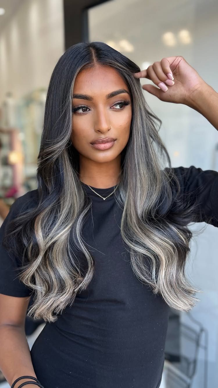Woman showcasing long dark hair with dramatic blended blonde ribbon highlights