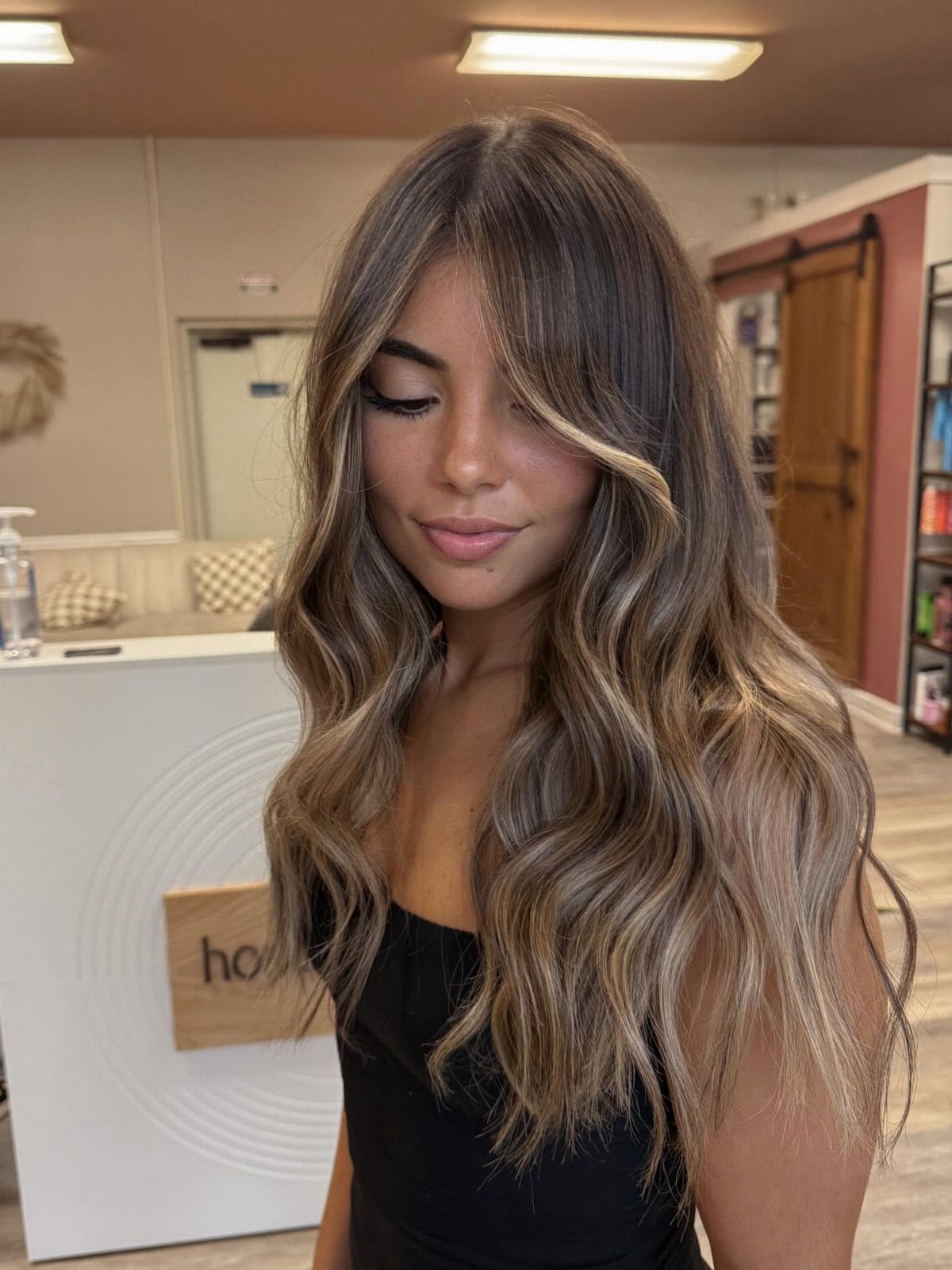 Woman showing long dark brunette hair with blended blonde balayage highlights