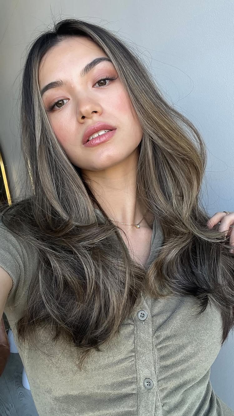 Woman showing long dark brown hair with soft bronze highlights and loose waves