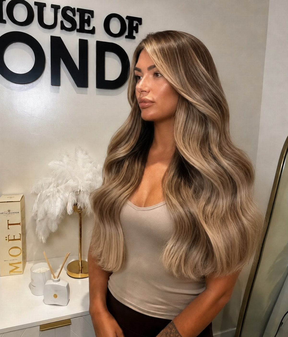 Woman displaying long wavy brunette hair fading into caramel-blonde ends