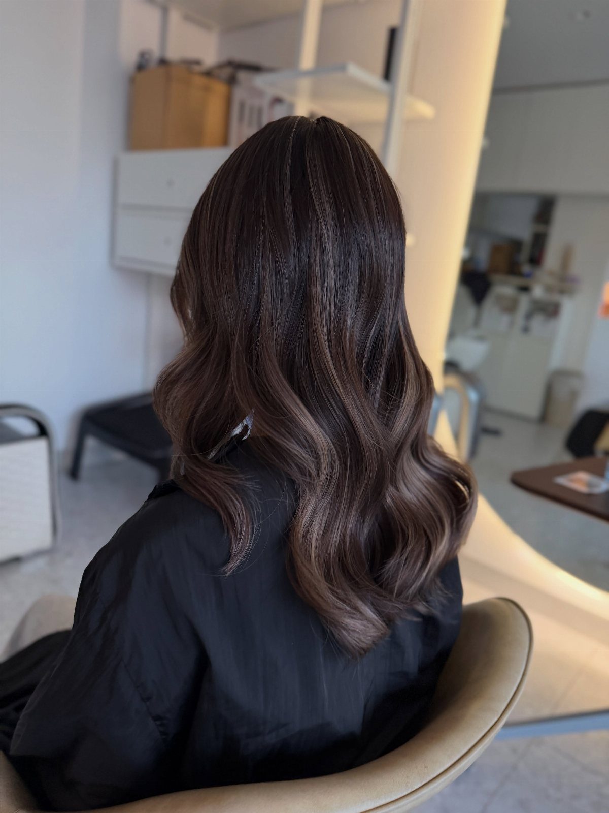 Long dark brunette waves show delicate, subtle highlights in a bright salon