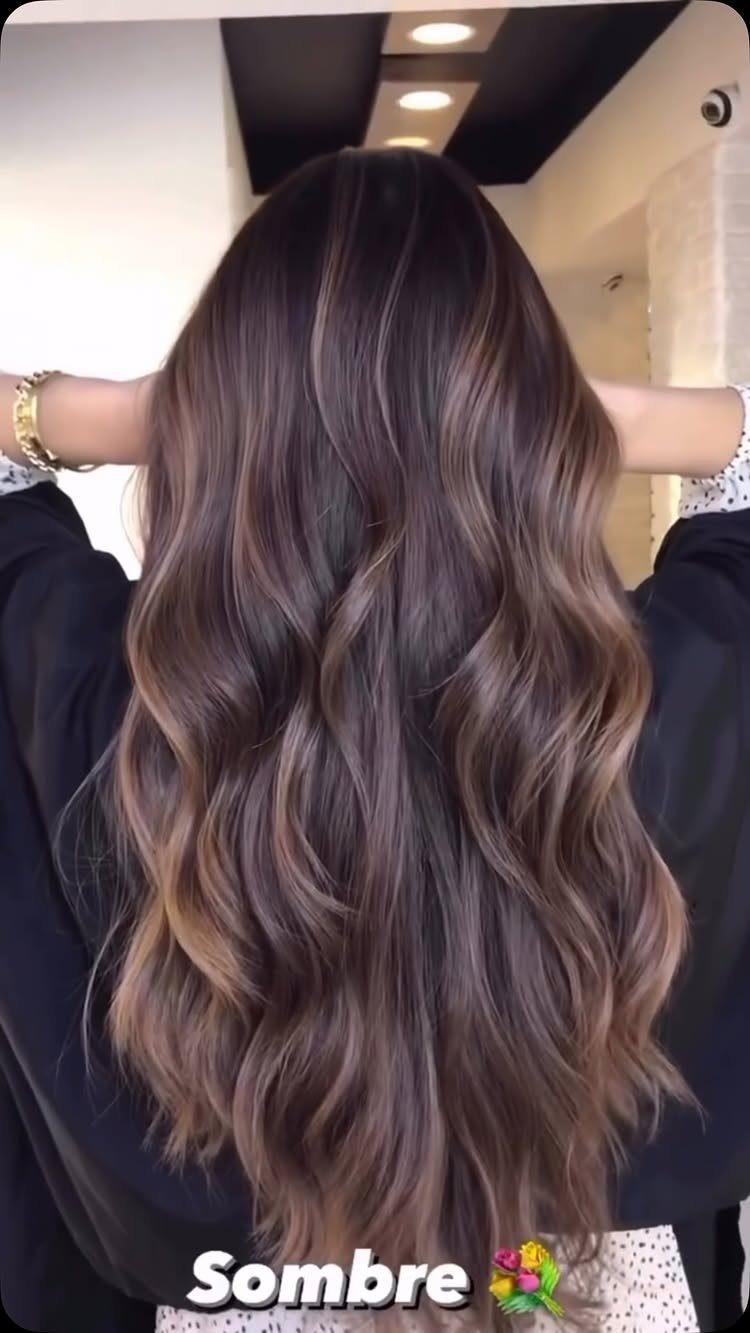 Long wavy brunette hair fades softly from dark roots to lighter brown ends