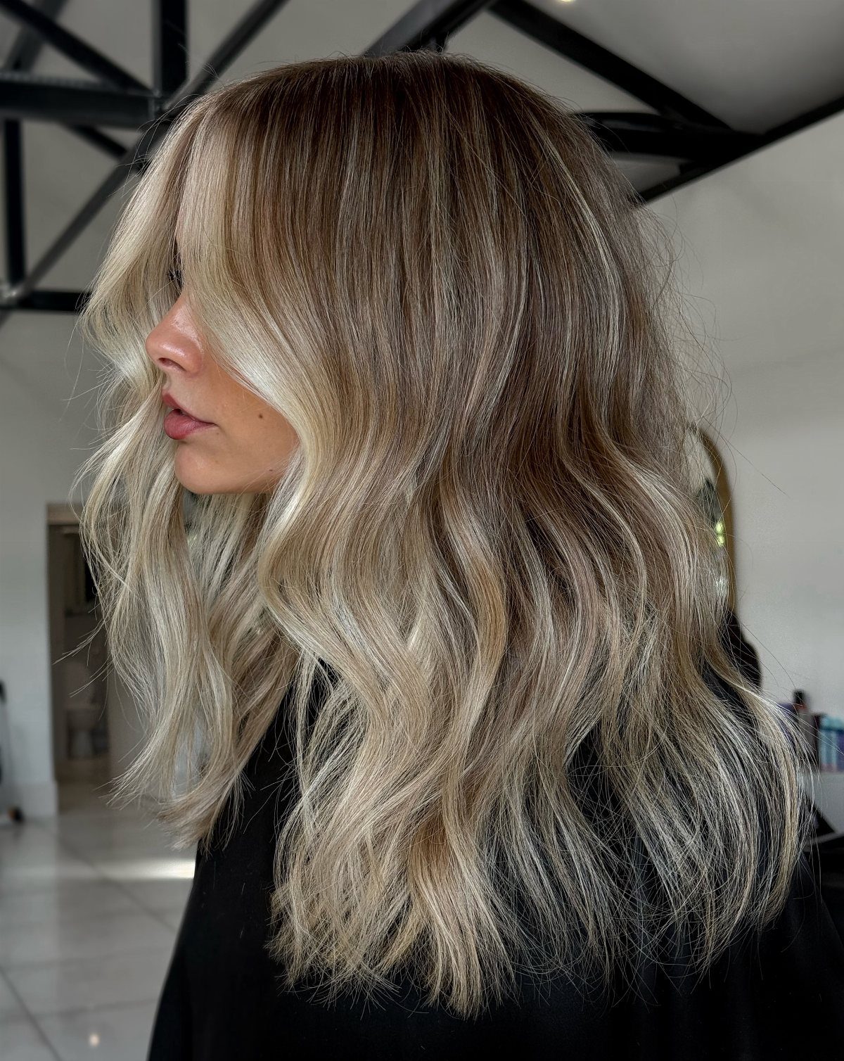 Woman with long wavy dark hair and beige-blonde highlights in a salon