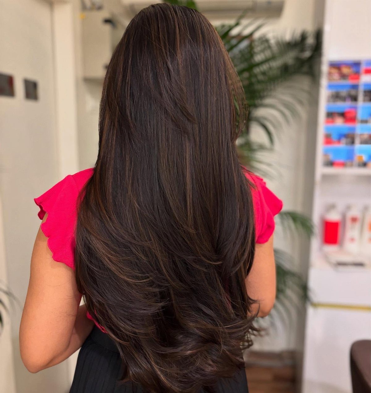 Long dark brown hair with subtle chocolate-brown highlights and curled layered ends