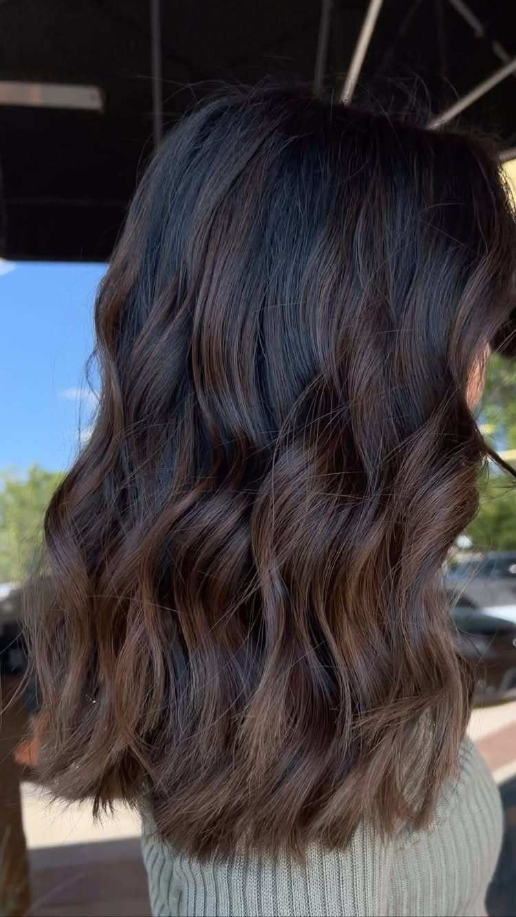 Wavy dark brown hair with subtle smoky brown highlights