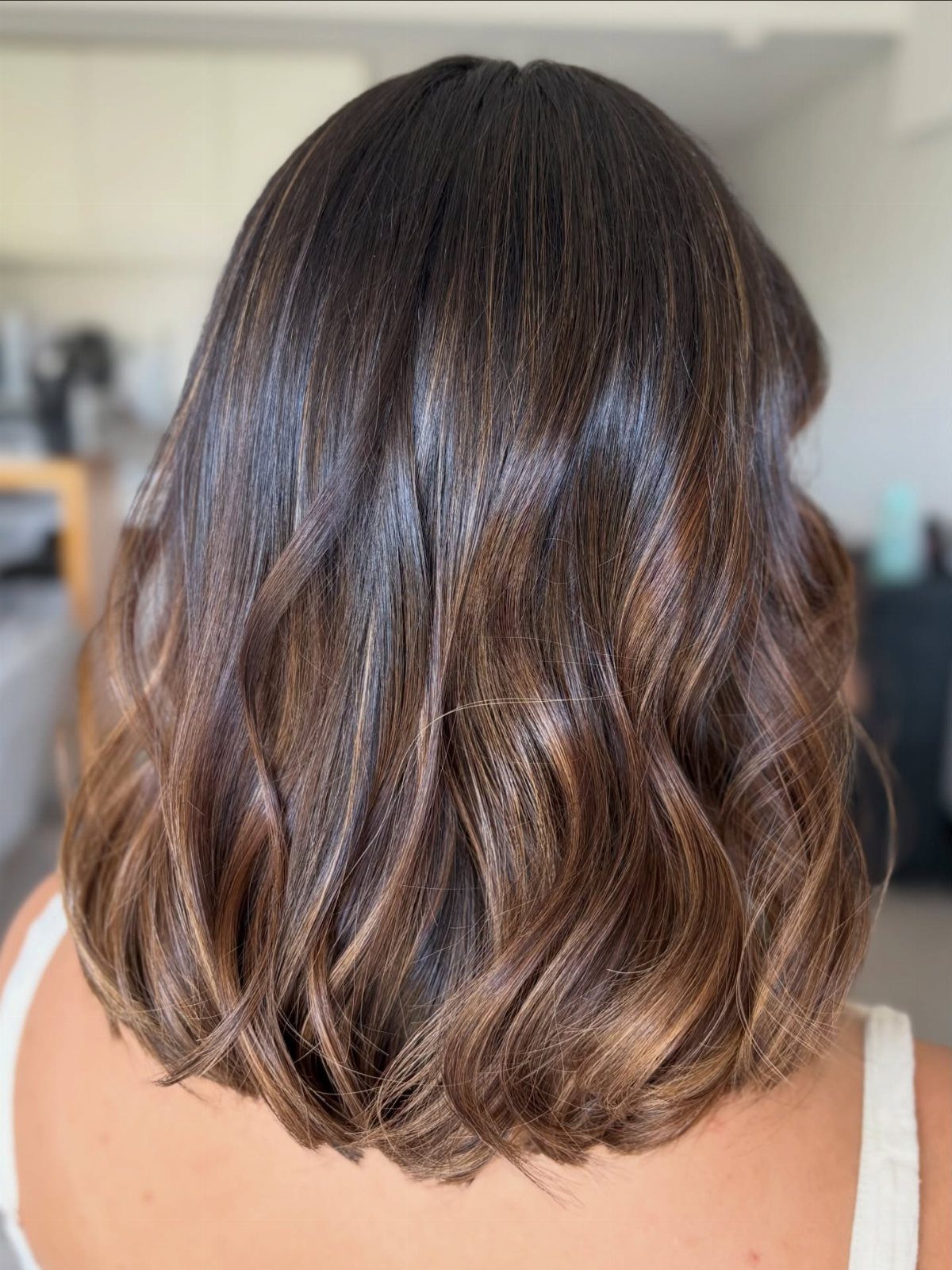 Short dark brown bob with subtle warm highlights through the curled ends