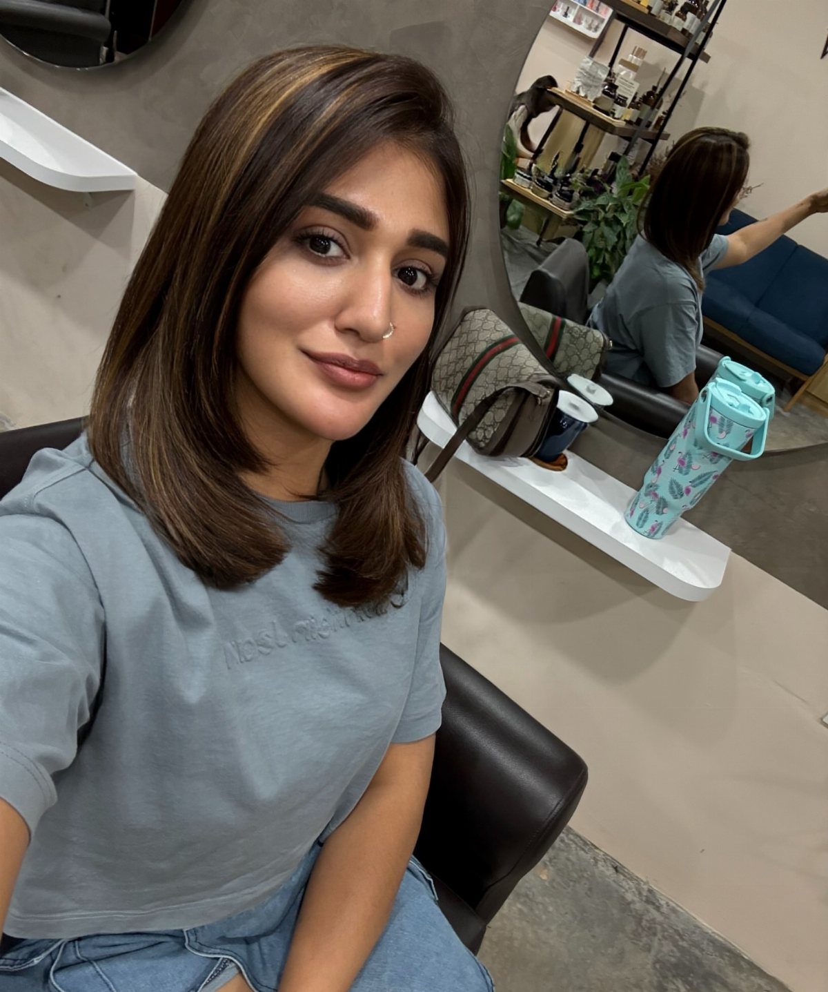 Woman showing shoulder-length dark brown hair with subtle partial highlights in a salon