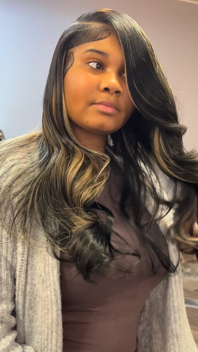 Woman with dark layered hair, side part, and lighter highlights in loose waves