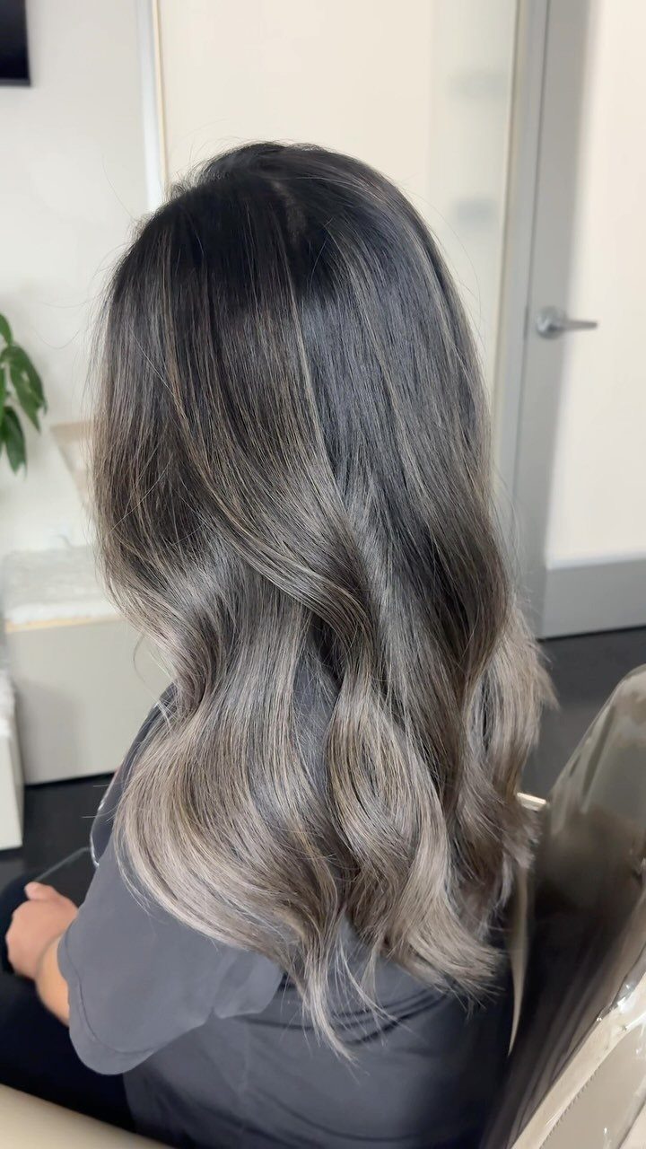 Long dark hair with cool mushroom-gray highlights in loose waves