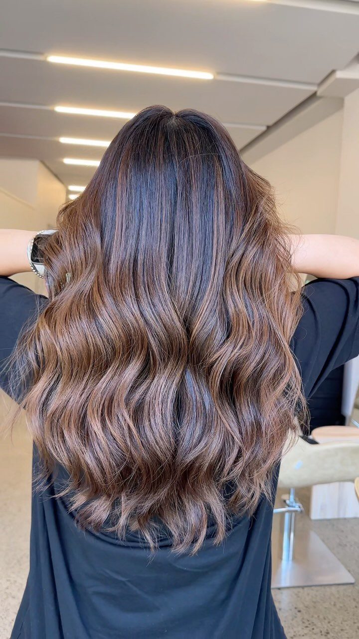 Long wavy brunette hair with softly blended warm brown balayage highlights