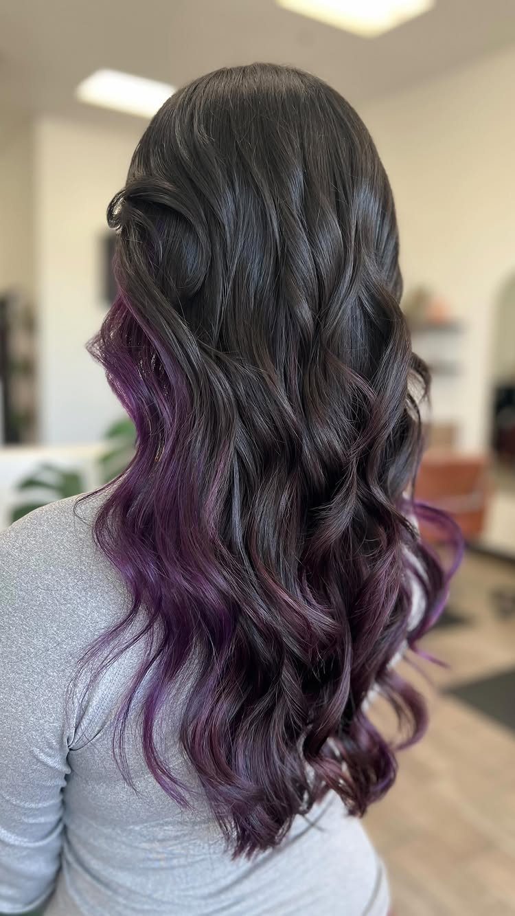 Long dark waves reveal purple peekaboo highlights beneath the top layers