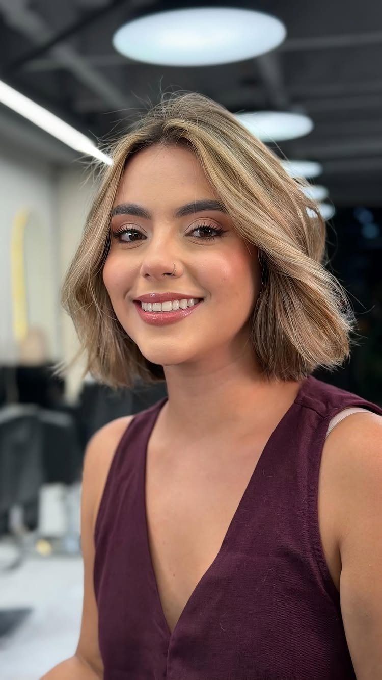 Woman with short beige-blonde balayage highlights in a salon