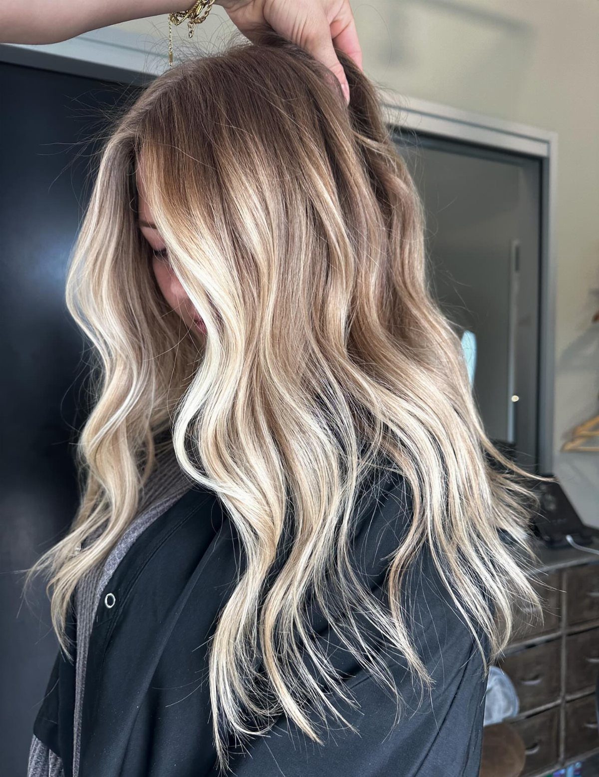 Long blonde waves with dark roots and dimensional highlights in a salon