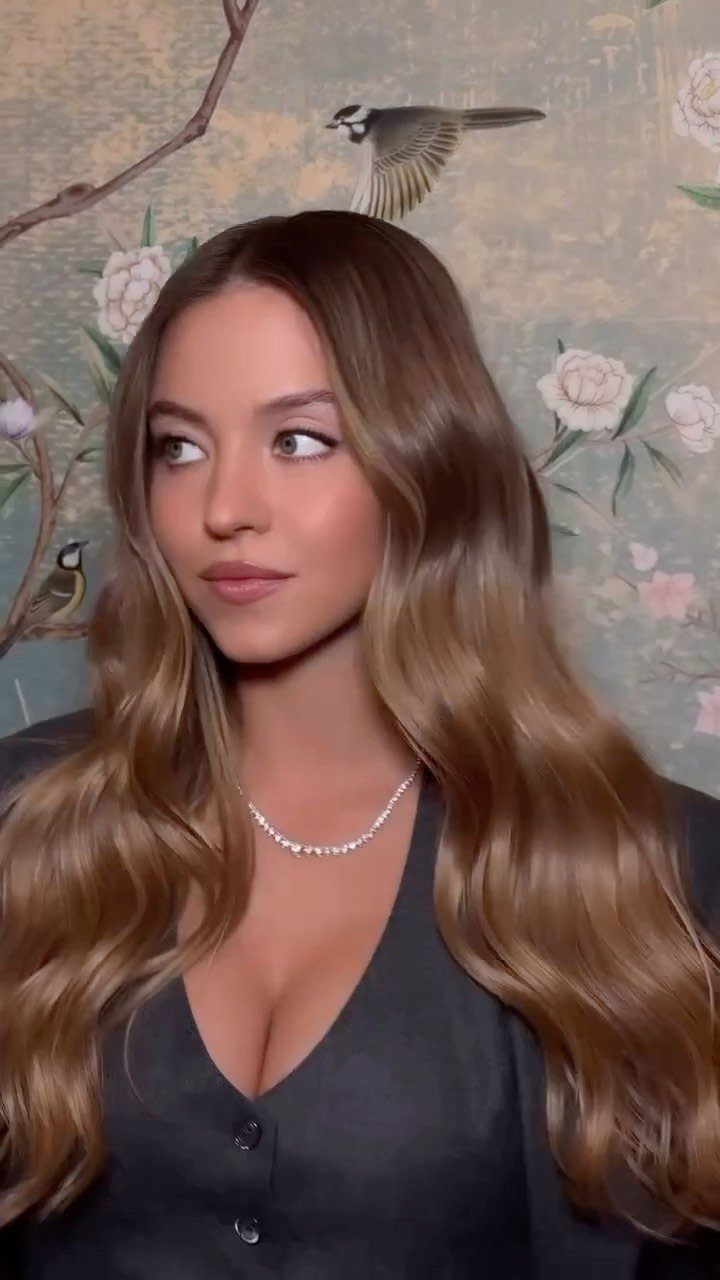 Woman with long dark dirty blonde waves and darker roots