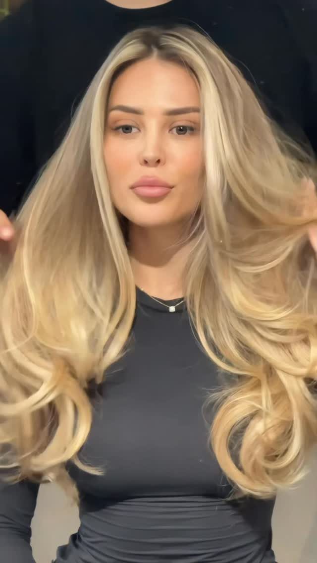 Woman with long blonde balayage, darker roots, and softly blended lighter strands