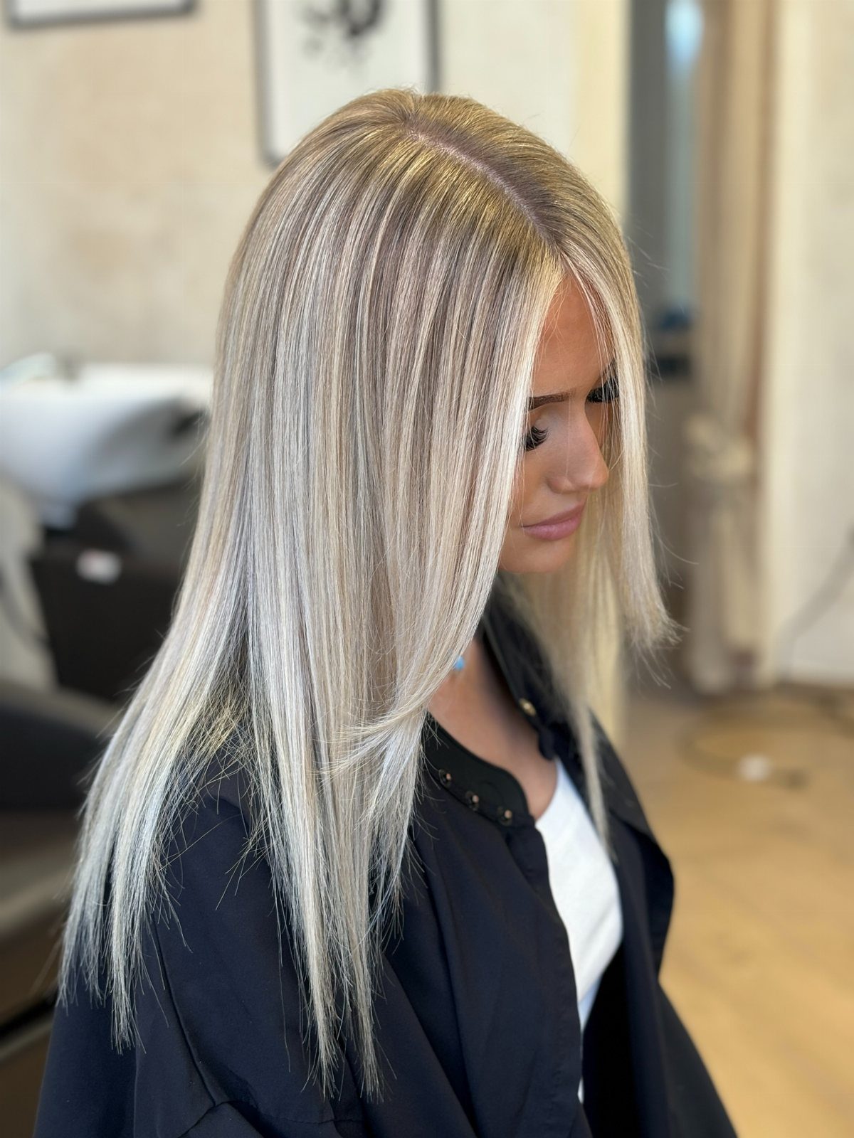 Long dirty-blonde hair with bright pale blonde highlights in a salon