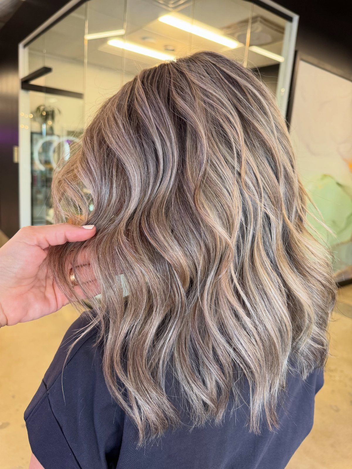 Long wavy brunette hair blended with cool blonde highlights in a salon
