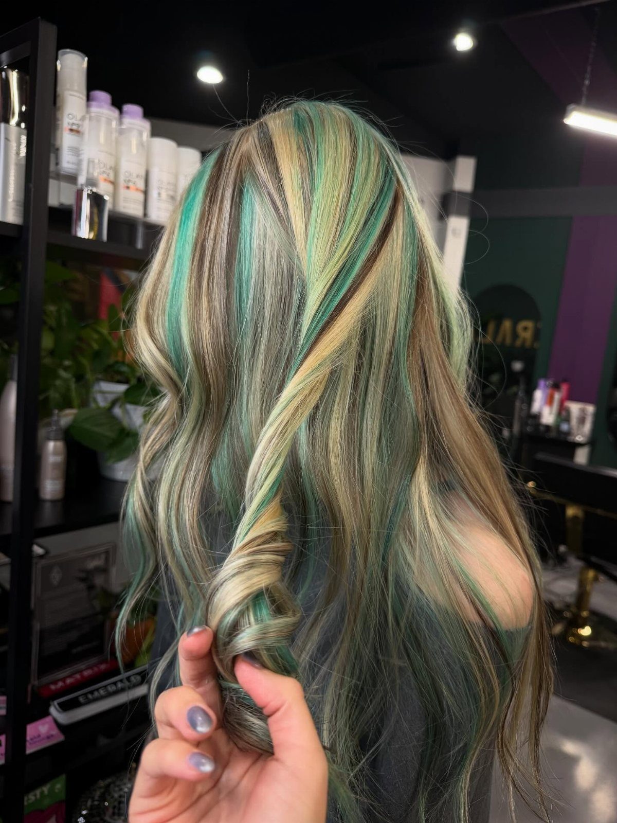 Blonde hair with mint-green highlights twisted by hand in a salon
