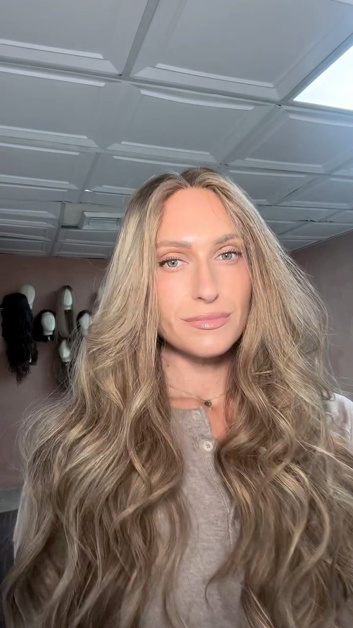 Woman showcasing long, wavy sandy blonde hair with lighter highlights