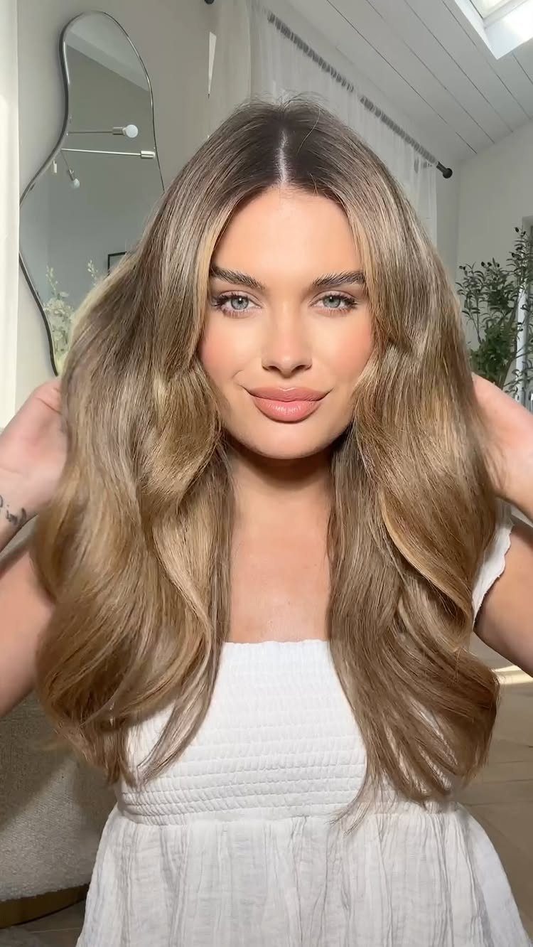 Woman with long wavy dirty blonde hair and soft, subtle highlights