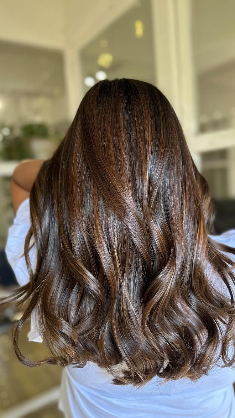 Long brunette hair with delicate caramel babylights styled in loose glossy waves