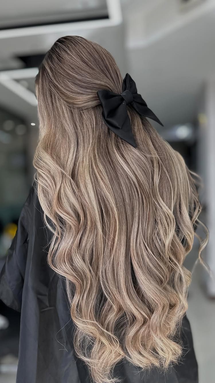 Long wavy balayage hair gathered with a large black bow