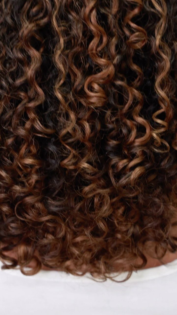 Tightly curled brunette hair with warm caramel balayage highlights
