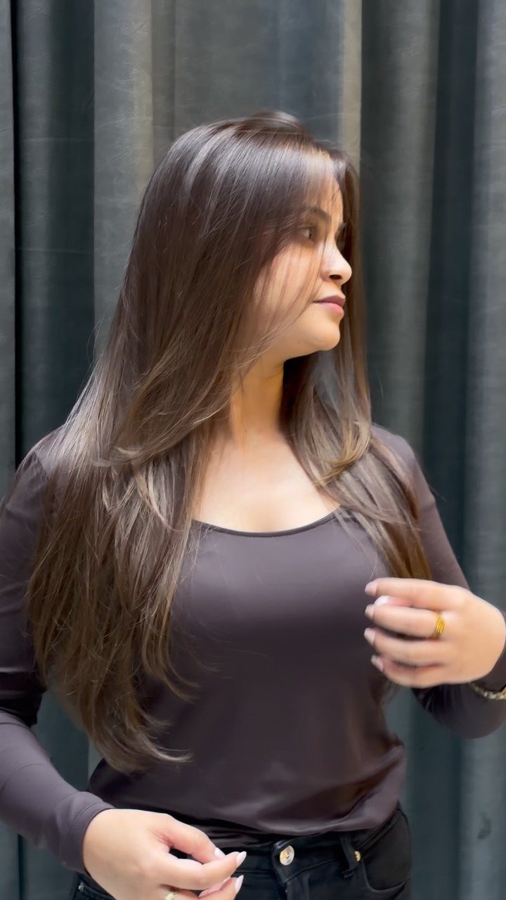 Woman showing long brown balayage hair with subtle lighter waves