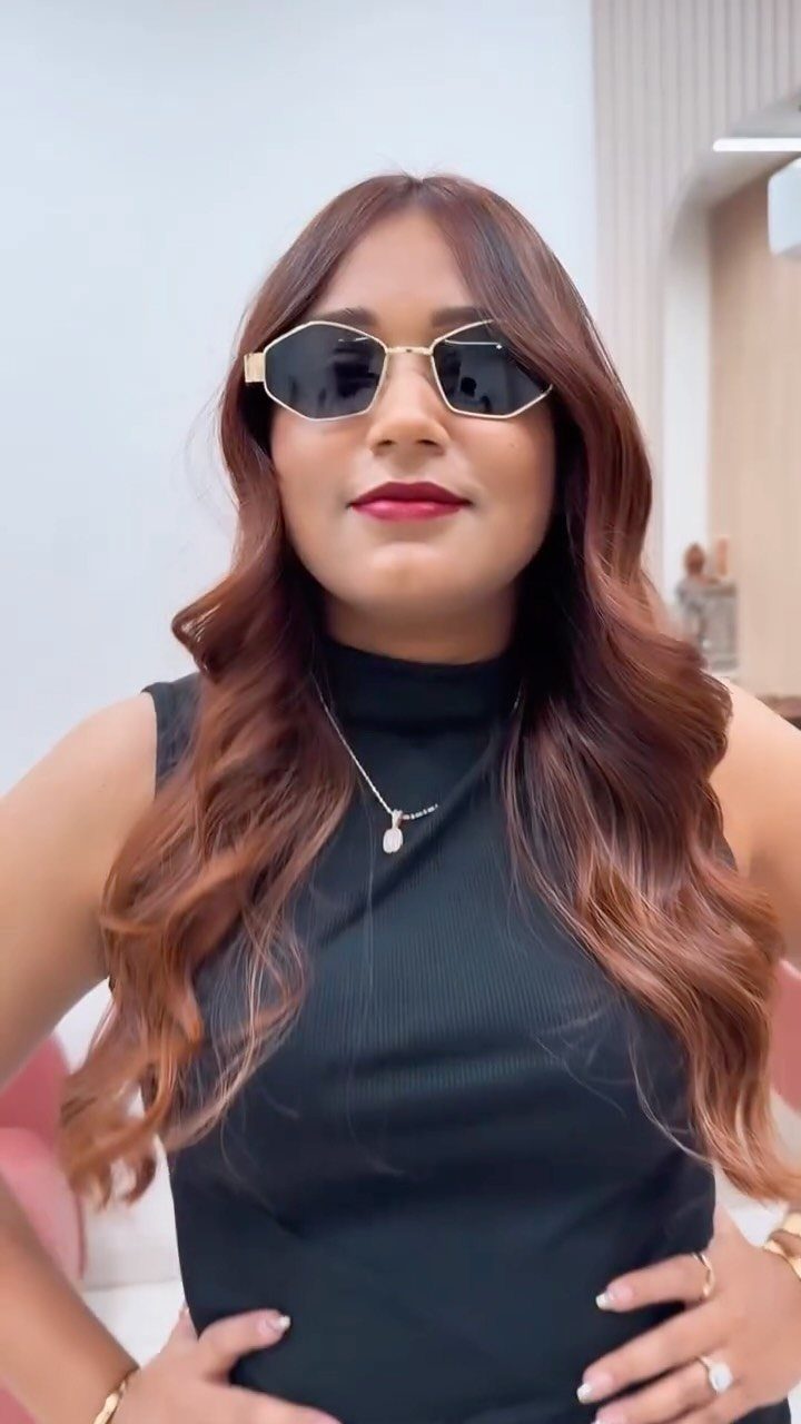Woman with long auburn-brown waves and caramel balayage wearing sunglasses