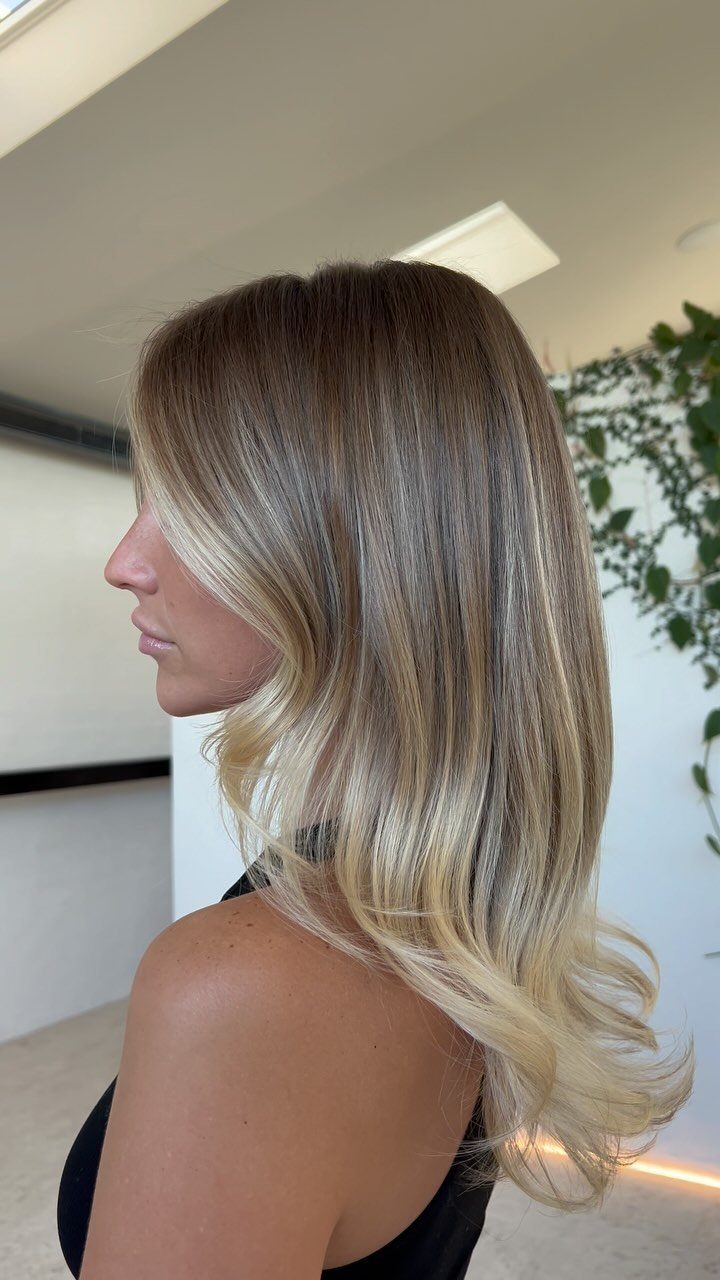 Woman's long dark-rooted hair blending into beige and golden blonde lengths