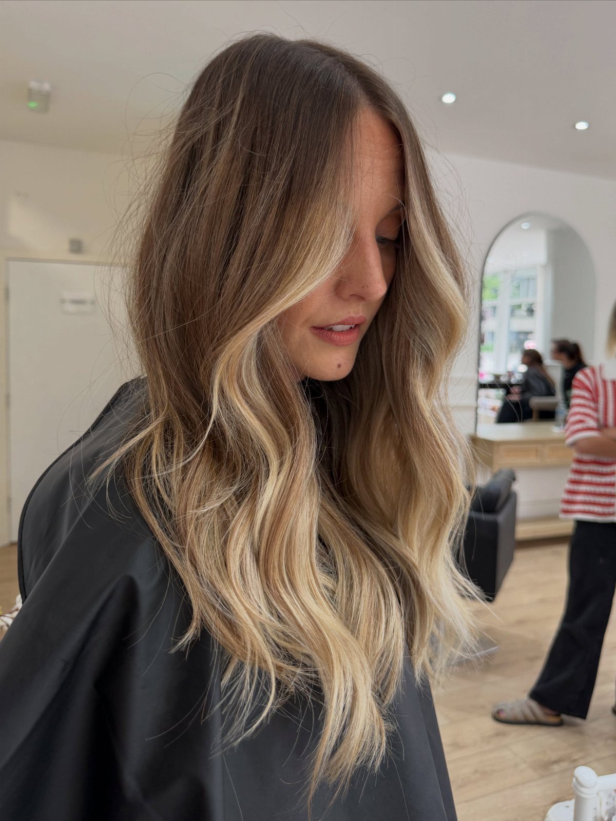 Long wavy brunette hair with blonde balayage ribbons framing a woman's face
