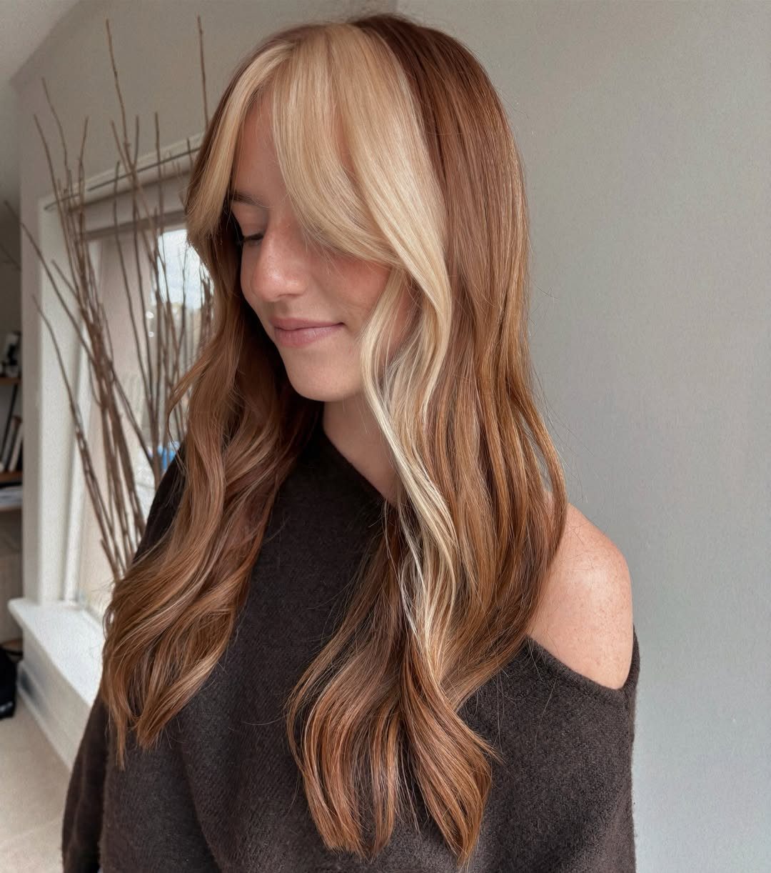 Woman with long wavy brown hair and warm copper and blonde balayage