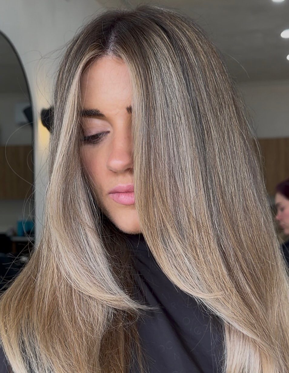 Long straight ash-brown hair with pale blonde highlights in a salon