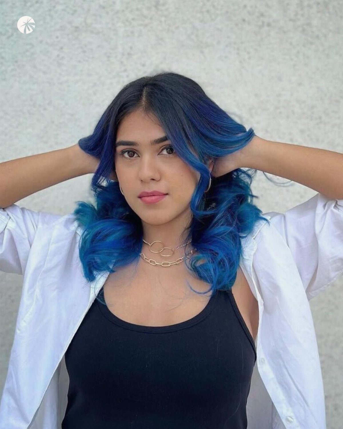 Woman displaying long dark brown hair with vivid blue highlights and curled ends