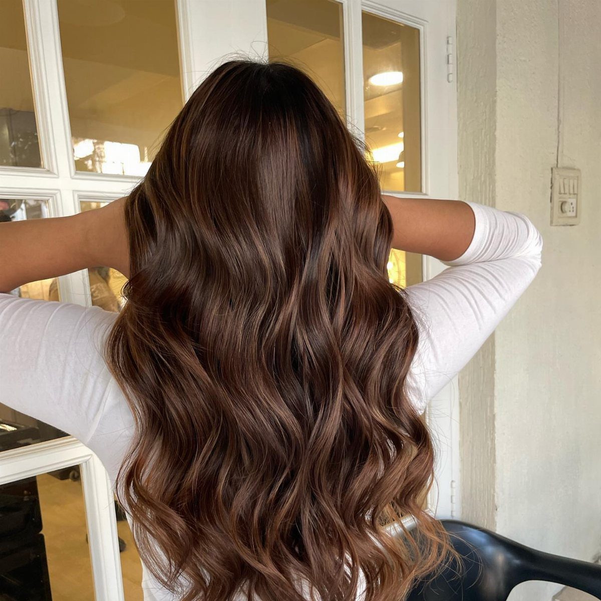 Long wavy brunette hair with subtle warm chestnut tones and dark roots