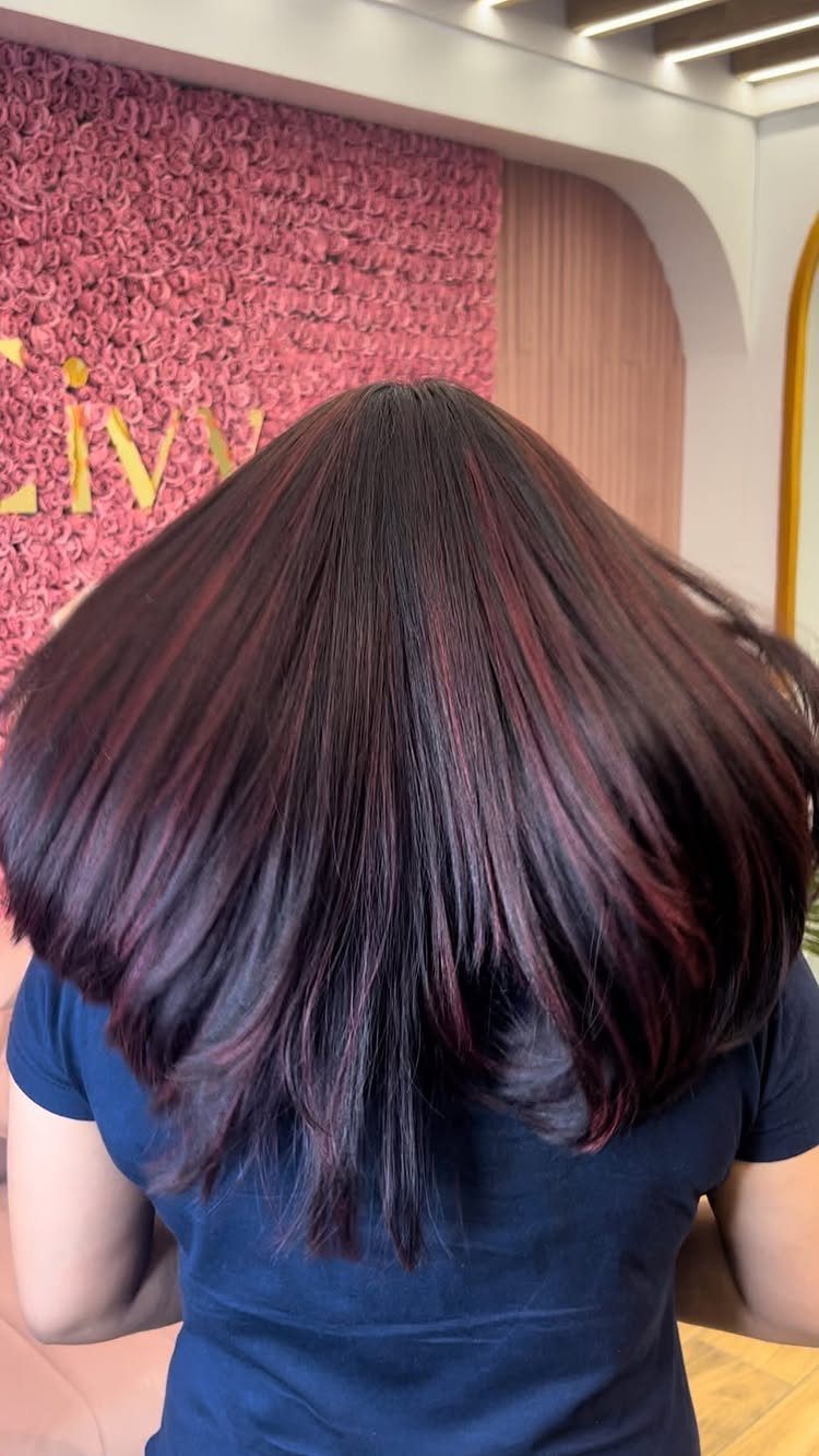 Long dark hair with cherry-red highlights cascading over a blue shirt