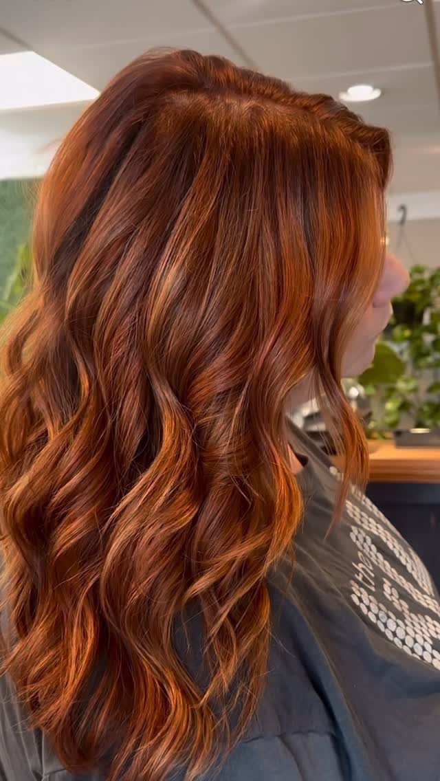 Wavy auburn hair shows darker reddish-brown lowlights in a salon