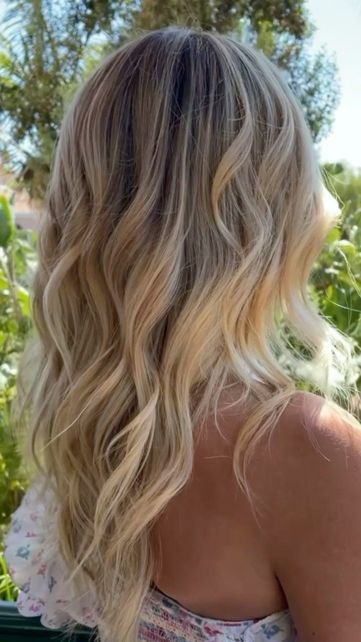 Wavy brown hair with blonde highlights viewed from behind outdoors