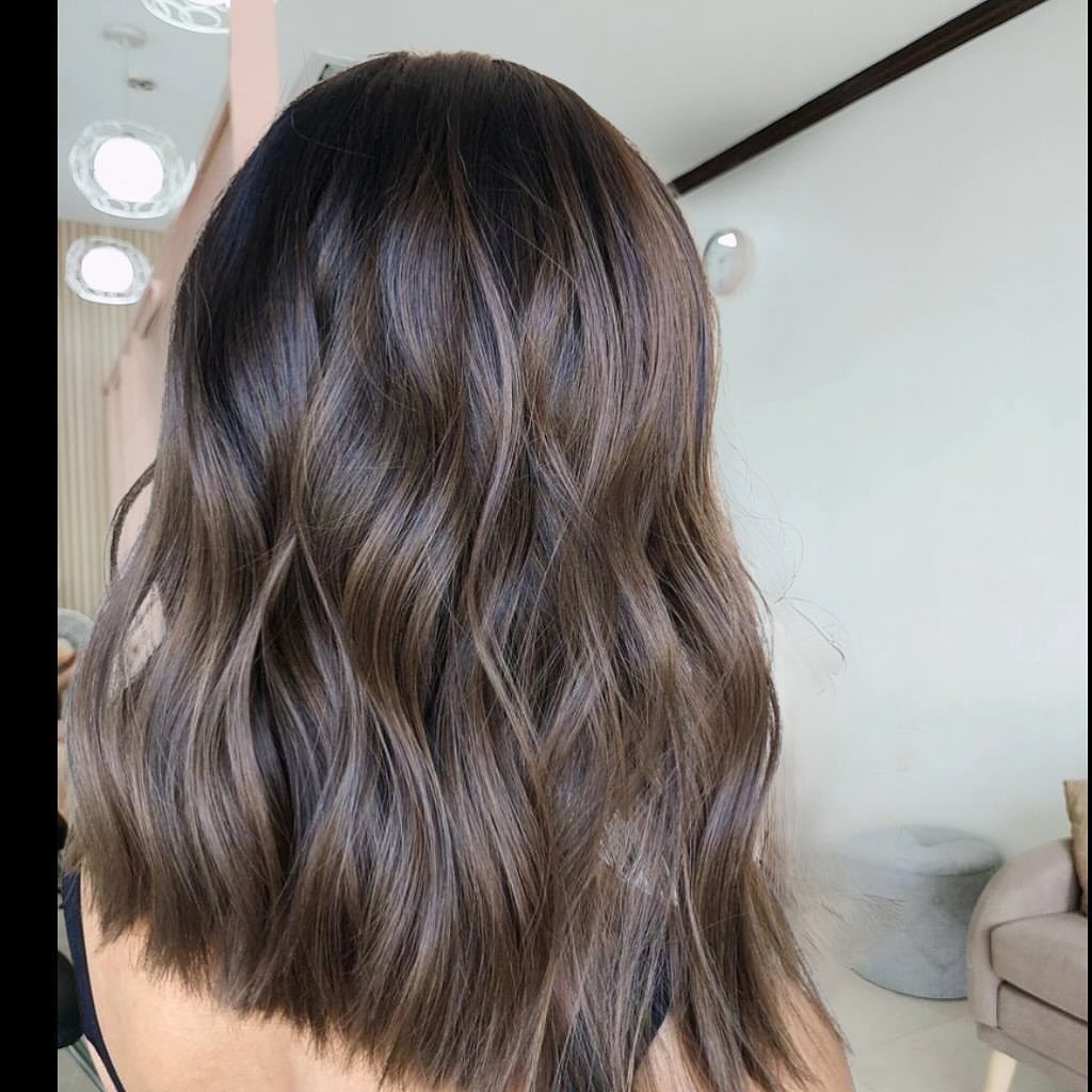 Wavy dark brown hair with subtle coffee-brown lowlights in a salon