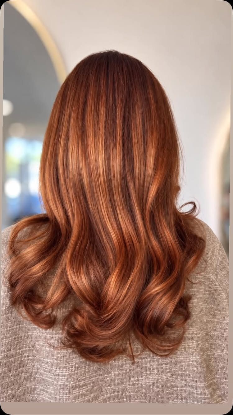 Long auburn hair with copper highlights and softly curled ends
