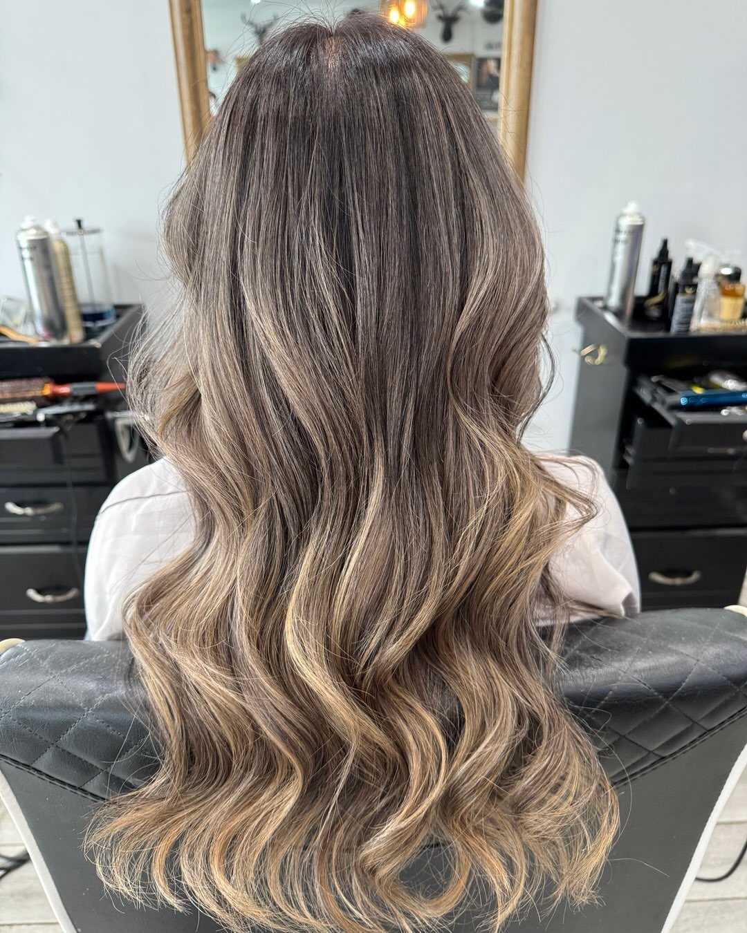 Long wavy hair fading from dark brown roots to ash-blonde ends