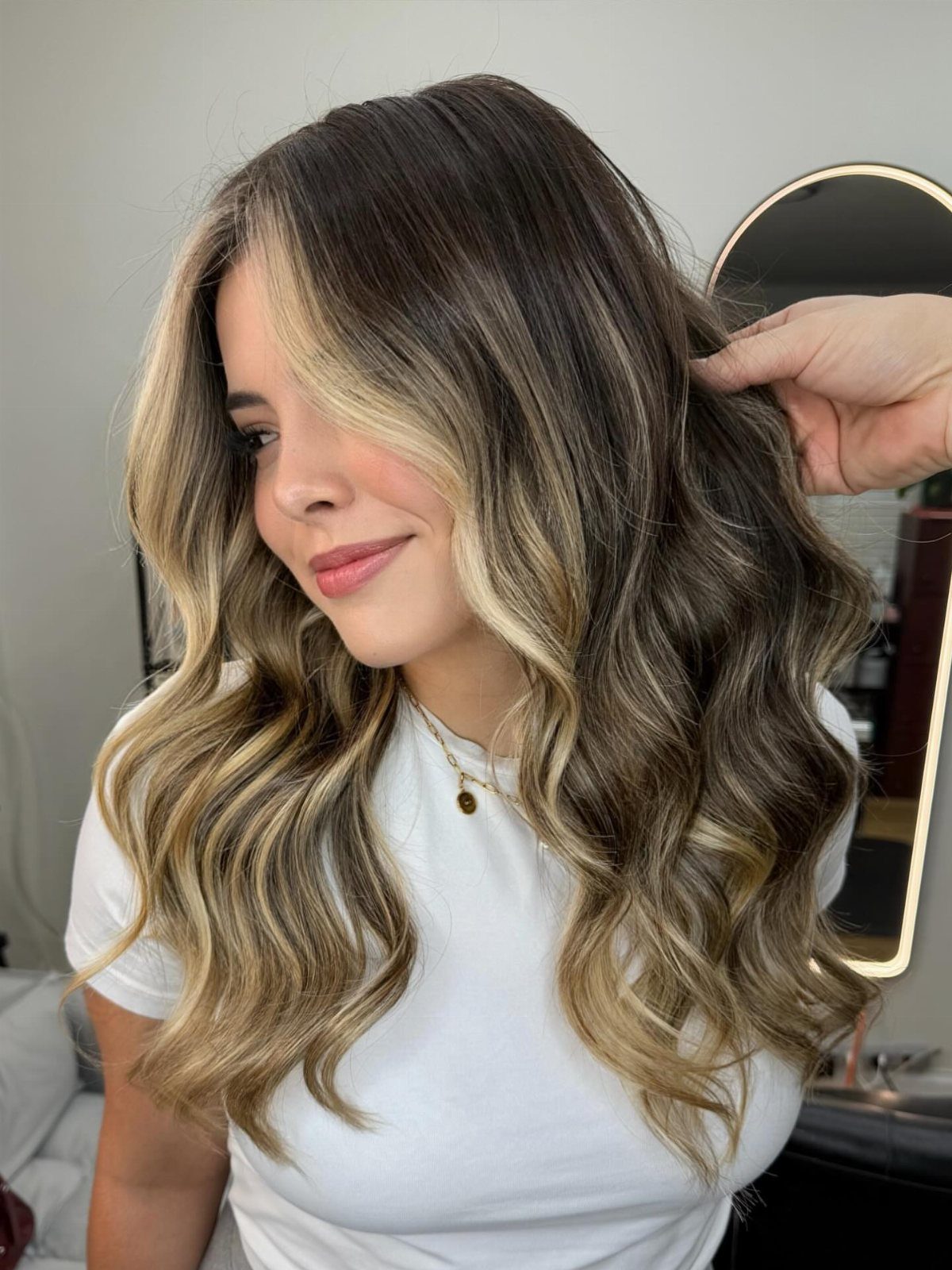Woman showing brunette balayage with soft caramel face-framing money-piece highlights